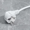 A close-up of a white electrical plug on a grey marble-like surface. Produktbild-Vorschau