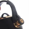 Close-up of the handle and spout of a black kettle with gold accents. Náhled obrázku produktu