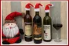 A festive arrangement of wine bottles with Santa hats, a Santa Claus plush toy, and a glass of red wine. Náhled obrázku produktu