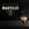 A steaming cup of coffee sits on a dark wooden surface, with the Martello Cafe logo in the background. Produktbild-Vorschau