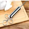A meat injector is placed on a wooden cutting board next to a piece of raw meat. Voir les images du produit