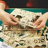 Hands assembling a wooden 3D puzzle of a heavy truck. Náhľad obrázku produktu