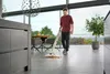 A man is using a floor cleaner in a modern kitchen with large windows overlooking a landscape. Anteprima dell’immagine prodotto