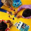 Children are assembling LEGO DOTS pieces on a yellow table. Anteprima dell’immagine prodotto