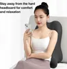 A woman is sitting on a bed, leaning against a back support pillow and using her phone. Produktbild-Vorschau