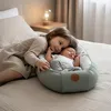 A young girl is leaning over a baby sleeping in a babynest on a bed. Podgląd zdjęcia produktu