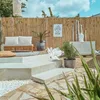 An outdoor seating area with a bamboo fence, a bench, plants, and decorative items. Produktbild-Vorschau