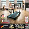 Two women are in a bright, modern living room setting, one using a treadmill and the other assembling it. The image is overlaid with various marketing badges and text. Produktbild-Vorschau