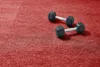 Two black dumbbells are placed on a red carpeted surface. Produktbild-Vorschau
