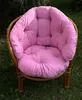 A pink cushion set for a rattan garden chair, placed outdoors on grass. Produktbild-Vorschau