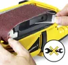 A close-up shot of a person's hands adjusting a sanding belt on a yellow power tool. A circular icon with crossed wrenches is visible in the lower right corner. Produktbild-Vorschau
