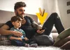 A father and son are sitting on a couch watching TV, with batteries overlaid on the image. Podgląd zdjęcia produktu