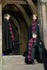 Three young people in Gryffindor robes and scarves stand on stone steps in a castle-like environment. Náhled obrázku produktu