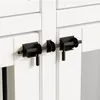 A close-up view of black metal latches on a white wooden surface, likely a cabinet or door. Produktbild-Vorschau