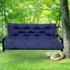 A dark blue cushion set on a swing in a garden setting, with a straw hat and sandals on the grass nearby. Produktbild-Vorschau