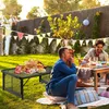 People enjoying a picnic in a backyard with a foldable camping table. Produktbild-Vorschau