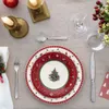 A Christmas-themed table setting with plates, cutlery, candles, and a festive centerpiece. Voir les images du produit