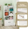 A white multi-purpose shelf unit with various items on display, including toys and books, set against a light green wall. Produktbild-Vorschau
