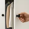 A hand is shown turning a black cabinet knob on a white cabinet door, with clothes visible inside the cabinet. Produktbild-Vorschau