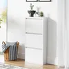 A white shoe cabinet with three flip-down drawers stands against a white wall. A woven basket with a blanket and pillow is placed next to it. Small potted plants are on top of the cabinet. Anteprima dell’immagine prodotto