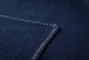 A close-up view of the corner of a dark blue blanket with white stitching. Produktbild-Vorschau