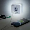 A Hama LED night light with a power outlet and two USB ports is mounted on a wall, charging a smartphone. A set of keys is on the table next to it. Voir les images du produit