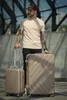 A man stands with two suitcases in an urban outdoor setting. Produktbild-Vorschau