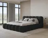 A bedroom with a large black upholstered bed, large windows with curtains, and a rug. Voir les images du produit