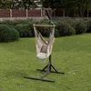 A hammock chair with a stand is set up on a grassy lawn in a backyard, with bushes and a fence in the background. Podgląd zdjęcia produktu