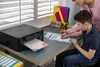 A boy and a woman are at a desk with a printer and school supplies. Podgląd zdjęcia produktu