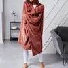 A person wearing a cozy blanket with sleeves and a hood in a living room setting. Podgląd zdjęcia produktu