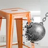 An orange metal bar stool is being struck by a wrecking ball, causing it to shatter. Náhľad obrázku produktu