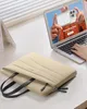 A person is using a laptop on a desk, with a laptop bag in the foreground. Produktbild-Vorschau