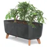 A dark gray planter with a marbled texture sits on four brown legs, holding a small green plant. Náhled obrázku produktu