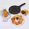 A pancake pan with smiley face molds, along with finished smiley face pancakes, fruit, and juice. Produktbild-Vorschau