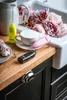 Three milk frothers are displayed on a wooden countertop next to a cup of coffee and flowers. Produktbild-Vorschau