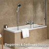 A modern bathroom with a bathtub, showerhead, and faucet, featuring a glass shower screen and marble-like wall tiles. Produktbild-Vorschau