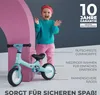 A child is standing next to a balance bike, with marketing text and warranty information. Produktbild-Vorschau