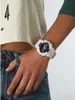 A person wearing a white Casio G-Shock watch on their wrist, with part of their torso and jeans visible. Produktbild-Vorschau