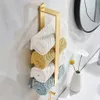 A gold towel rack with rolled towels in various colors mounted on a tiled wall. Voir les images du produit