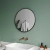 A modern bathroom with a round black mirror, a white sink, and copper faucets. Náhľad obrázku produktu