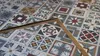 A close-up view of a patterned surface, possibly a countertop or wall, with a wooden object placed diagonally across it. Produktbild-Vorschau