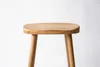 A close-up studio shot of a wooden stool on a white background. Produktbild-Vorschau