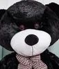 Close-up of a large black teddy bear's face, wearing a plaid bow tie. Podgląd zdjęcia produktu
