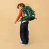 A young boy wearing a backpack and looking over his shoulder. Produktbild-Vorschau