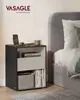 A bedside table next to a bed, with a phone charging on top. Produktbild-Vorschau