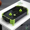 A mini air hockey table is placed on a white table, with a basketball and some stationery in the background. Náhľad obrázku produktu