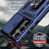 A blue phone case with a camera slider and ring holder is shown in a dynamic, angled shot against a rocky, mountainous background, suggesting durability and protection. Produktbild-Vorschau