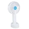 A white handheld fan with a blue center, resting on a white base, against a white background. Produktbild-Vorschau