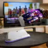 A hand holds a PlayStation Portal device with a game displayed on its screen, positioned above a white charging dock. In the background, a television displays a colorful image. Anteprima dell’immagine prodotto